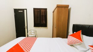 A hotel room with a bed, a wardrobe, and a chair. - OYO 2614 Demasto Homestay (Jember)