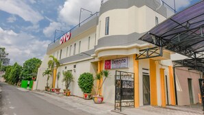 A modern building with a Demasto sign, featuring a curved facade, multiple windows, and a covered entrance. - OYO 2614 Demasto Homestay (Jember)