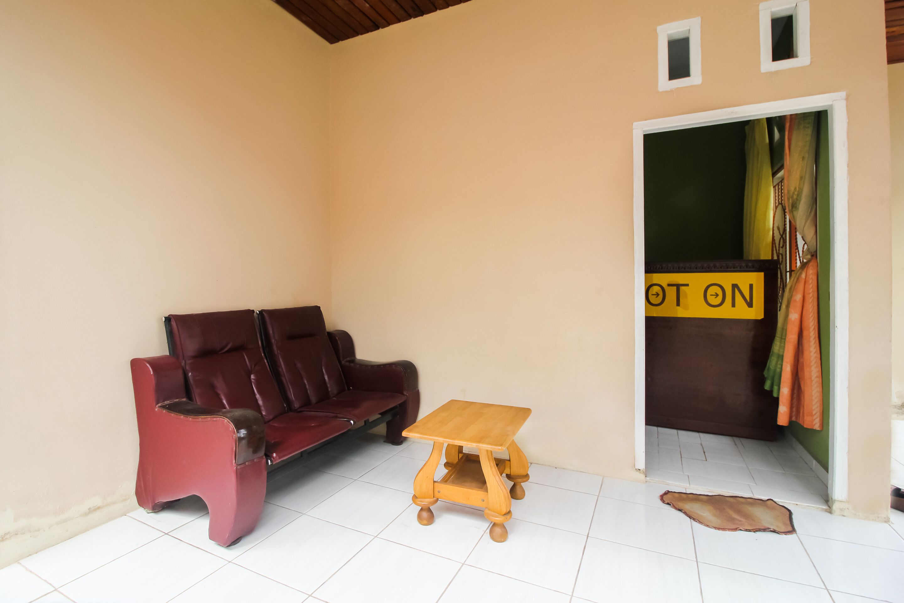 Une pièce avec un canapé rouge, une table en bois et une porte sur laquelle est affiché un panneau indiquant « CHAUD ».