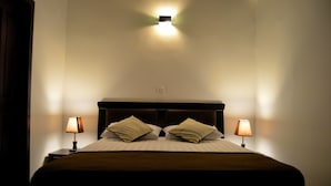 Hotellihuone, jossa on sänky, kaksi yöpöytävalaisinta ja seinään kiinnitetty valaisin.