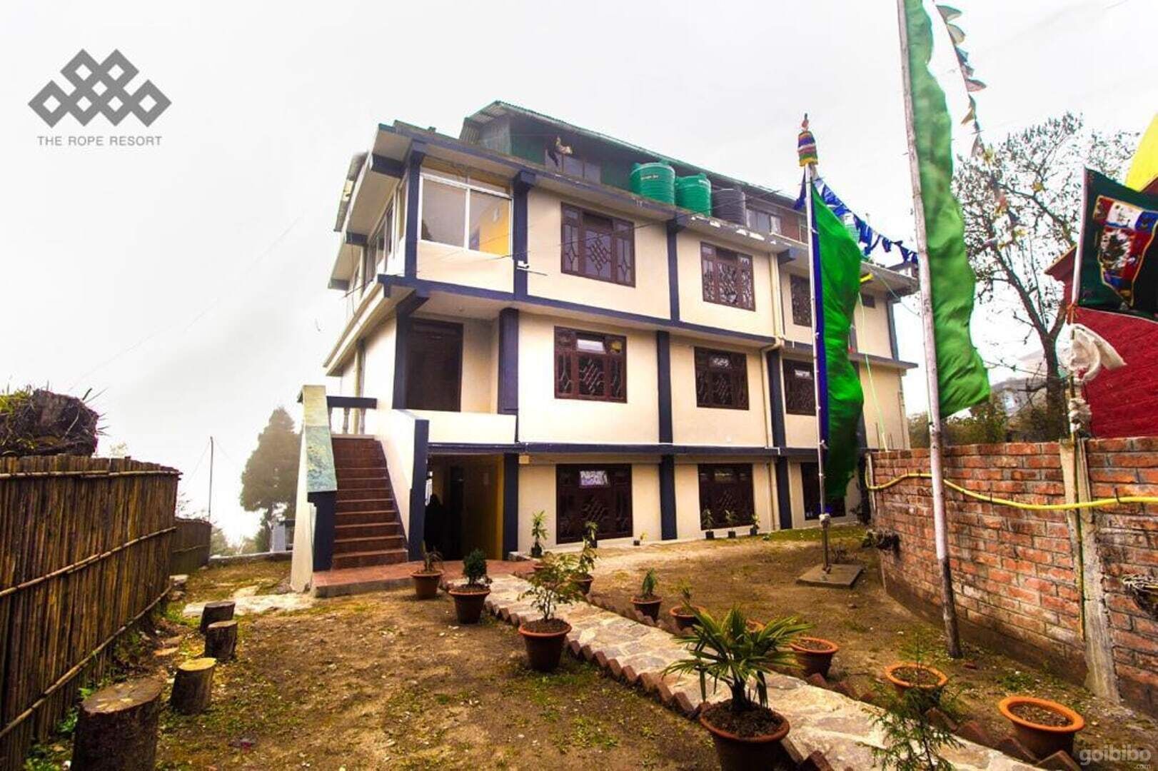 A multi-story building with a flat roof, a staircase leading to the entrance, and a flagpole with a flag.