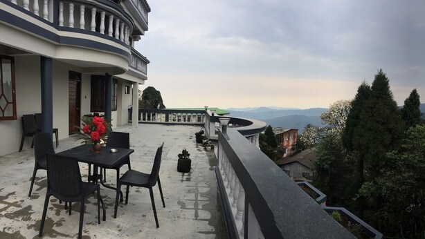 Une terrasse avec une table et des chaises, un pot de fleurs et une vue sur les montagnes.