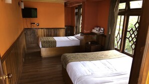 Une chambre d’hôtel avec deux lits, un plancher en bois, une télévision et une fenêtre donnant sur un paysage verdoyant.