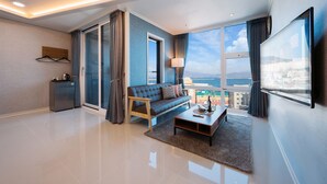A modern living room with a sofa, coffee table, and a view of the city through large windows.