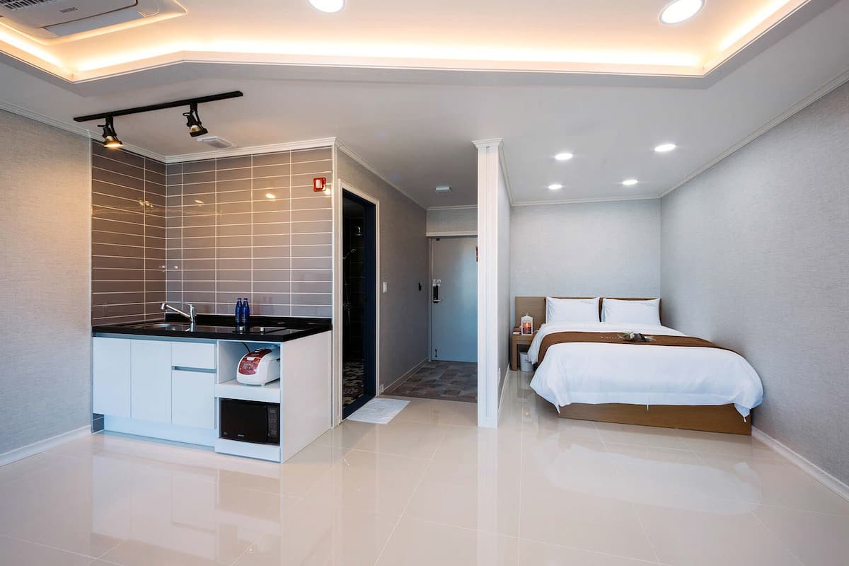 Quarto de hotel moderno com banheiro, uma cama e cozinha compacta.
