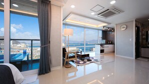 A modern living room with a large window, a sofa, a coffee table, and a view of the cityscape.