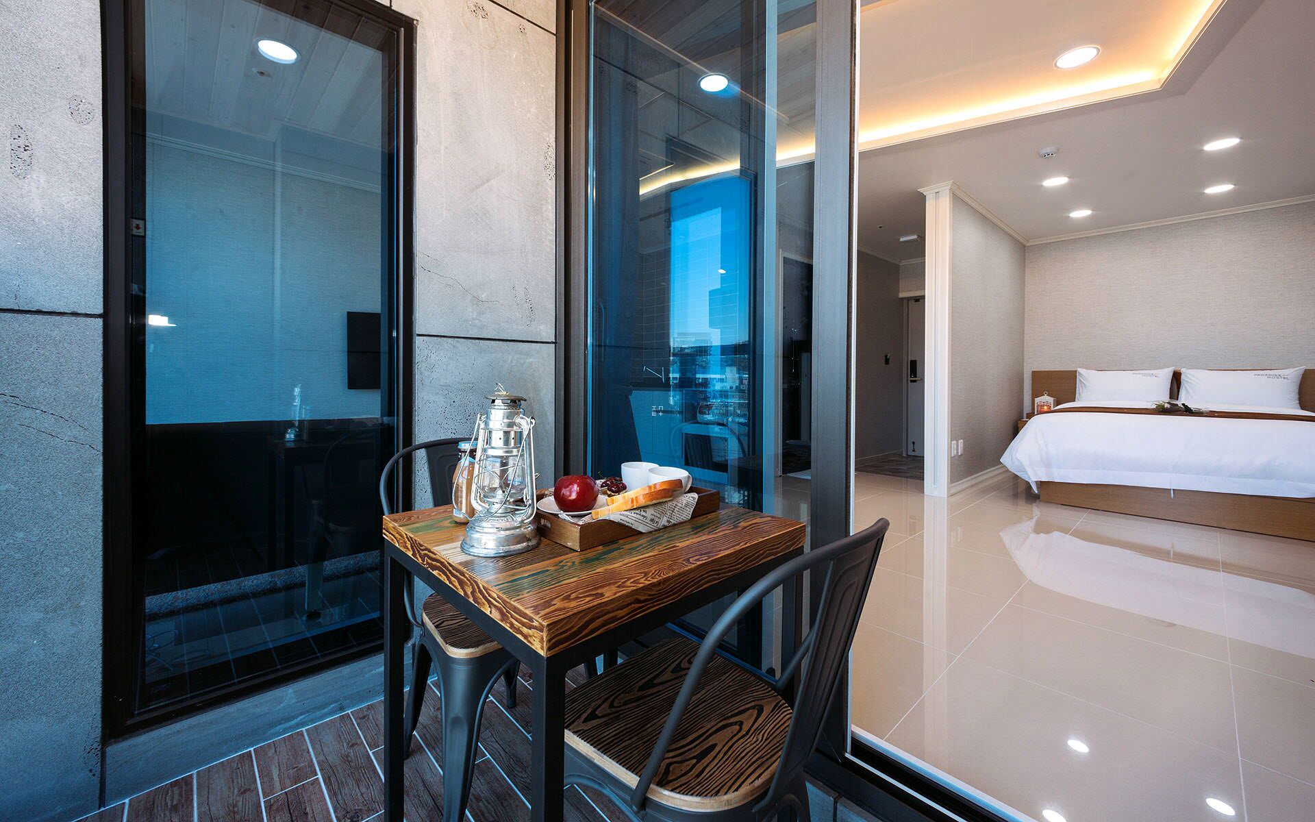 Una habitación de hotel moderna con una mesa de madera, un farol y un cuenco de fruta.