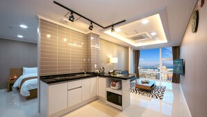 A modern kitchen with a large island, a dining area with a view, and a bedroom with a bed and nightstand.