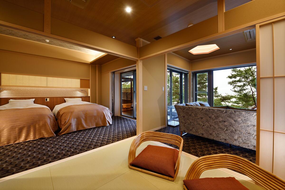 Ein Hotelzimmer mit zwei Betten, einer Sitzecke mit Blick und einem Balkon.