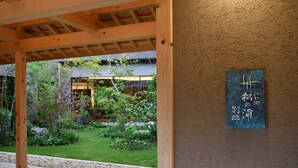 A covered outdoor area with a wooden structure and a garden view. - Biwako Mastunoura Bettei (Otsu)