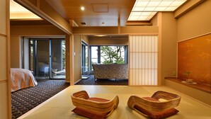 A traditional Japanese-style room with tatami flooring, a futon bed, a sliding door leading to a bathroom, and a view of a tree outside. - Biwako Mastunoura Bettei (Otsu)