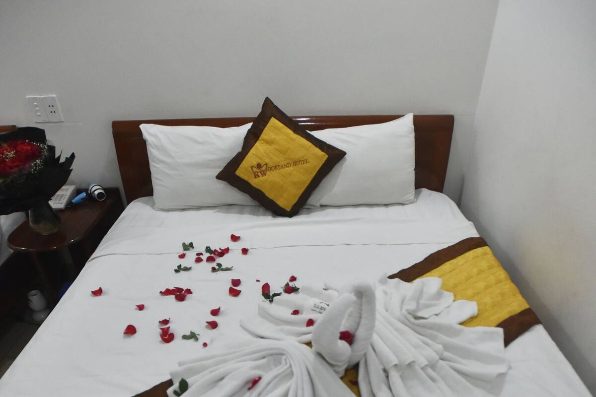 Una cama bien tendida con una colcha a rayas amarillas y marrones, almohadas blancas y una sola almohada amarilla con borde marrón.