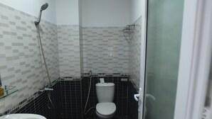 A small, tiled bathroom with a toilet, sink, and shower.