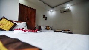 A hotel room with a bed, a wardrobe, and an air conditioning unit on the wall.