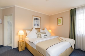 A hotel room with a bed, bedside lamps, a framed picture on the wall, and a window with curtains. - Hotel Landhaus Ambiente (Munich)