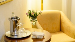 Una mesa redonda de madera con un dispensador de bebidas plateado, un vaso y un florero con flores.