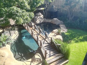 A wooden bridge over a clear pool with surrounding rocks and greenery. - Ikamu's lodge (Germiston)