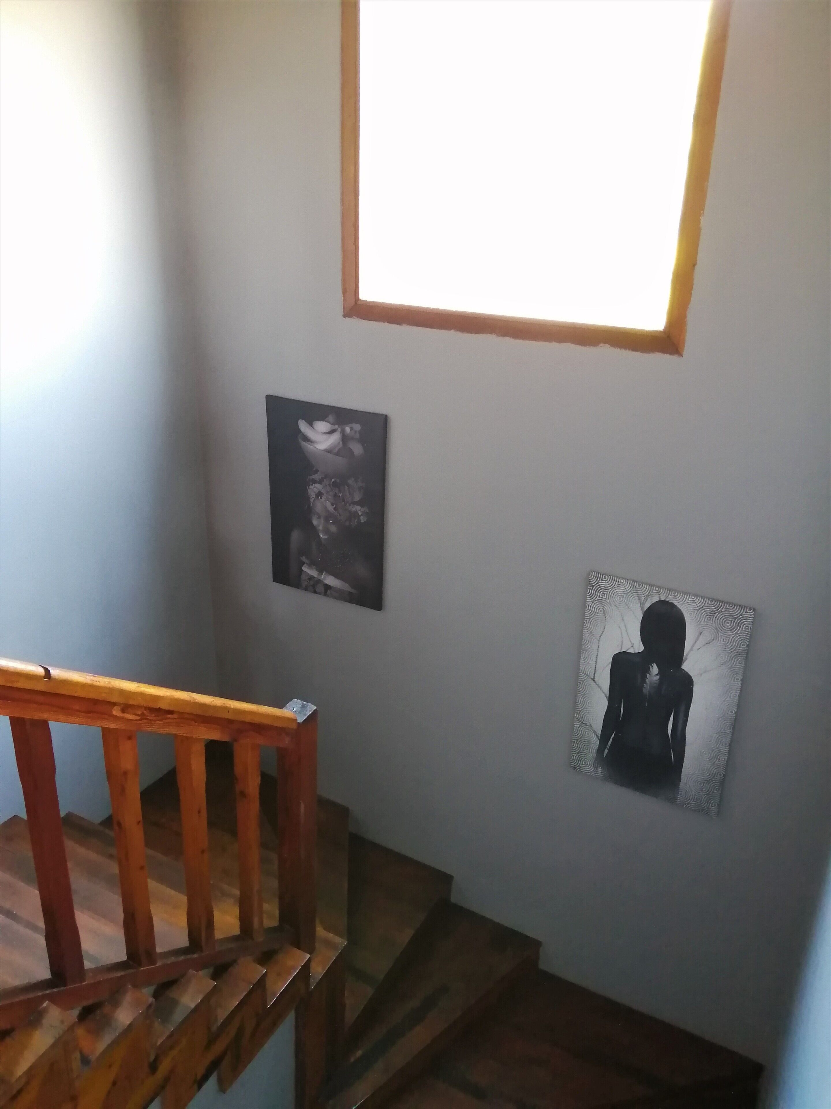Una escalera con barandas de madera y un pequeño ventanal en la parte superior.