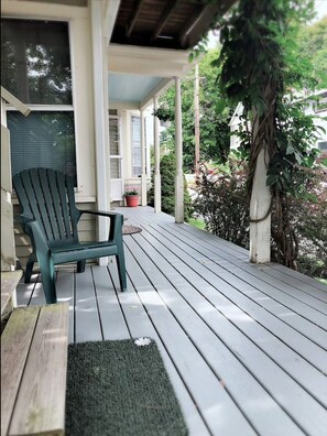 Relax on the covered porch with a comfortable Adirondack chair, surrounded by lush greenery and a serene atmosphere.