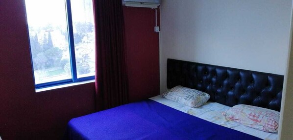 A room with a bed, a window, and a red wall. - Alsabah Hotel Apartments (Amman)