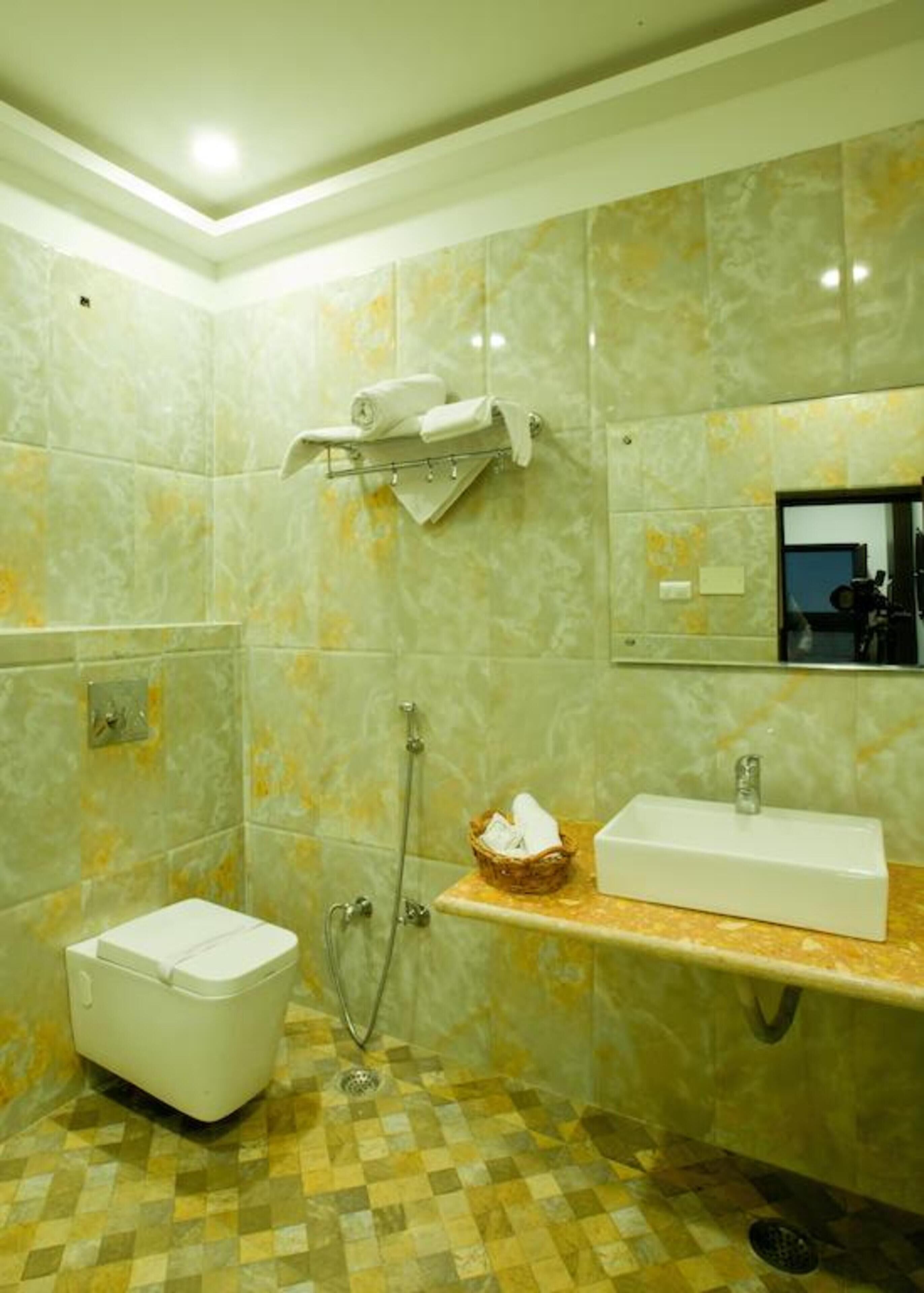A bathroom with a toilet, a sink, a shower, and a mirror.