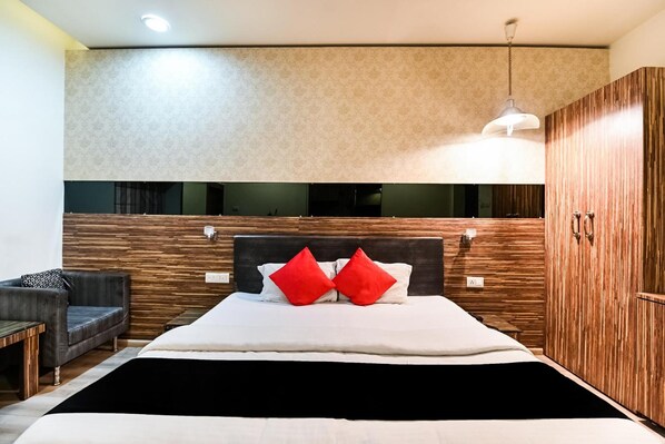 Una camera d'hotel moderna con un letto grande, una testiera in legno e uno specchio sopra il letto.