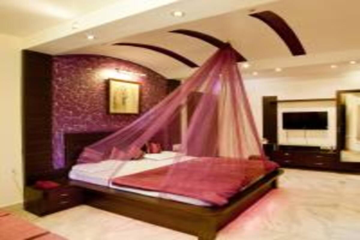 A bedroom with a canopy bed, a large mirror, and a painting on the wall.