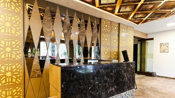 A reception area with a marble counter, geometric patterned walls, and a ceiling with recessed lighting. - Hotel Surpin Palace (Kota)
