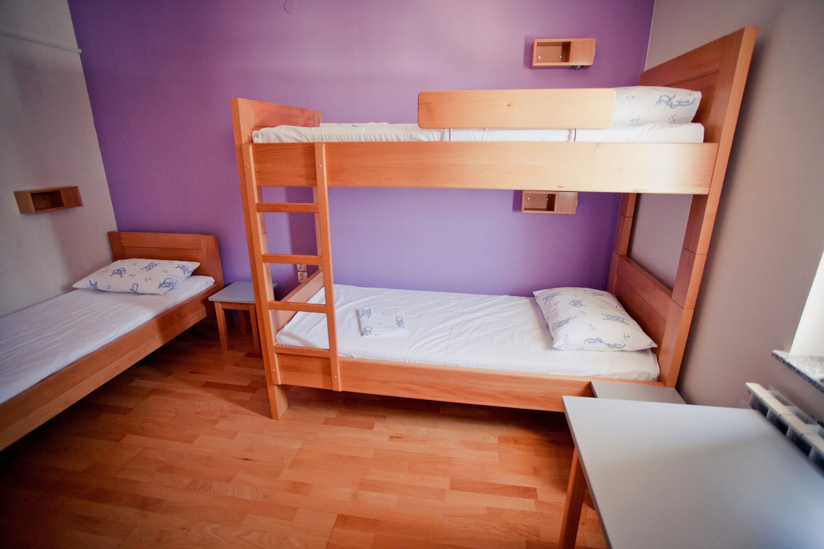 A room with two bunk beds, a small table, and a ladder.