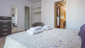 Une chambre à coucher moderne, dotée d’un grand lit, d’une armoire et d’une salle de bain visible à travers une porte ouverte.