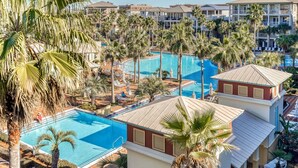 Ein Resort mit mehreren Schwimmbecken, umgeben von Palmen und Liegestühlen.