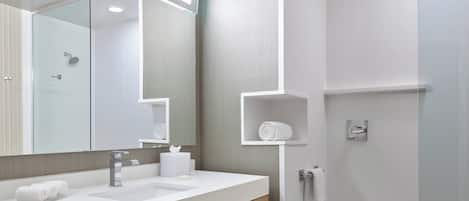 Un baño moderno con un espejo grande, un lavamanos y una ducha.
