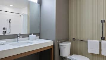 A modern bathroom with a white sink, mirror, and toilet.