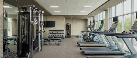 A gym with treadmills, weight machines, and a mirrored wall.