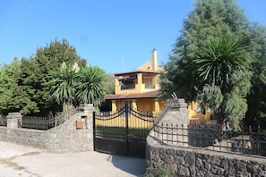 A yellow house with a stone gate and a red-tiled roof.