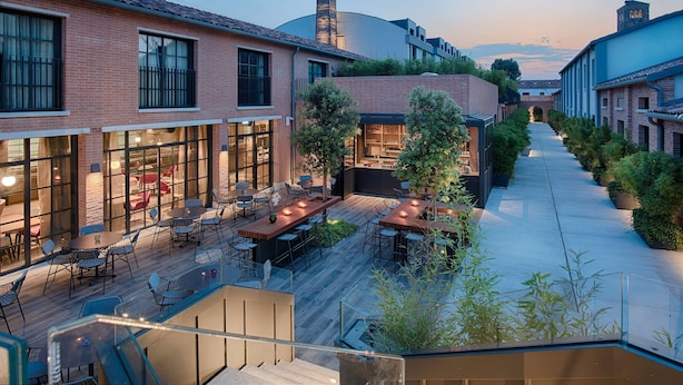 A courtyard with outdoor seating, brick buildings, and a staircase leading to an upper level. - NH Collection Venezia Murano Villa (Venice)