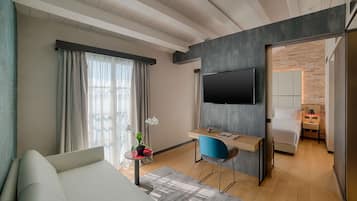 Una habitación de hotel moderna con una cama, un escritorio con una silla, un televisor y una pequeña mesa con una planta.
