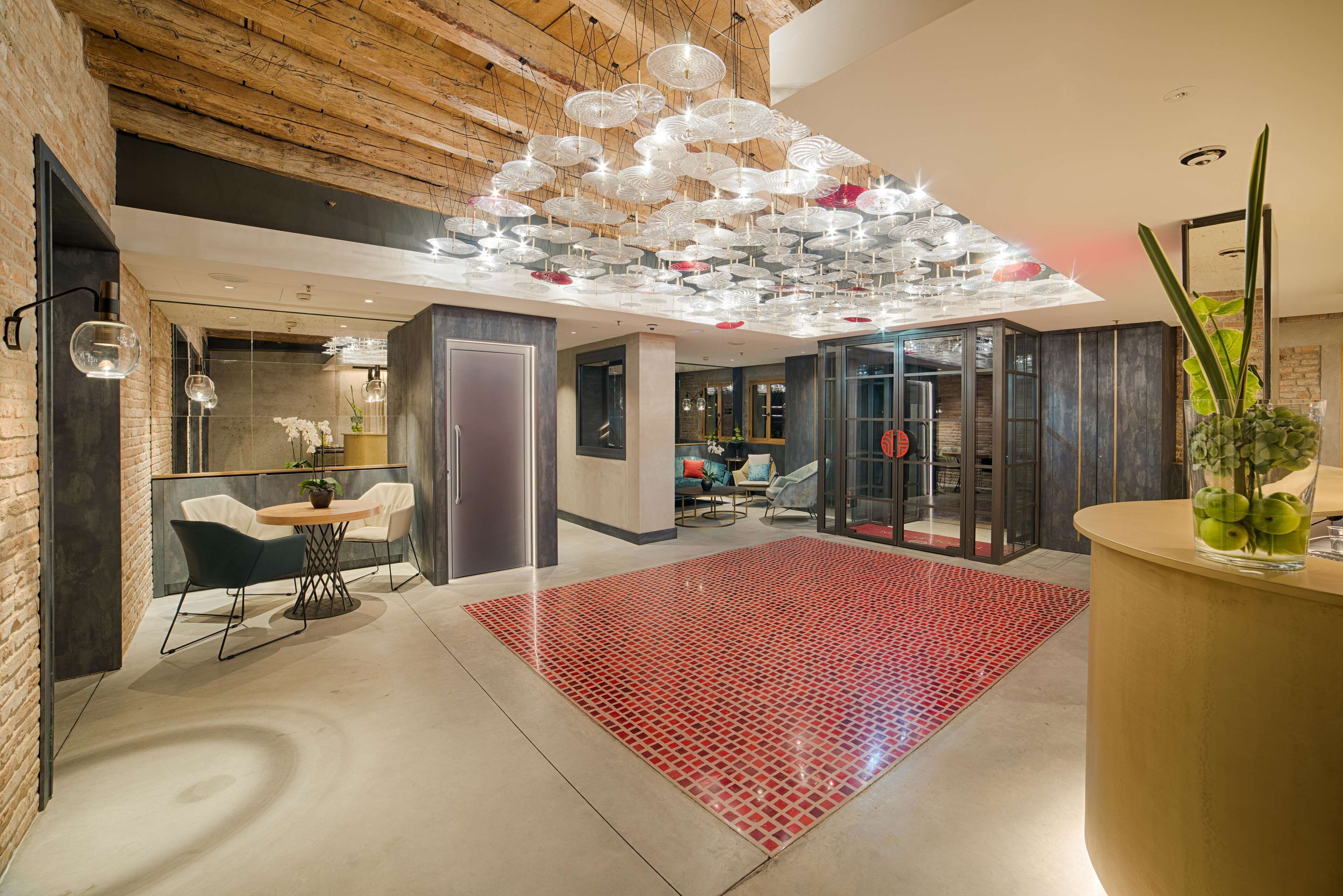 Un interior moderno con techo de madera, alfombra roja estampada y una lámpara de techo original.