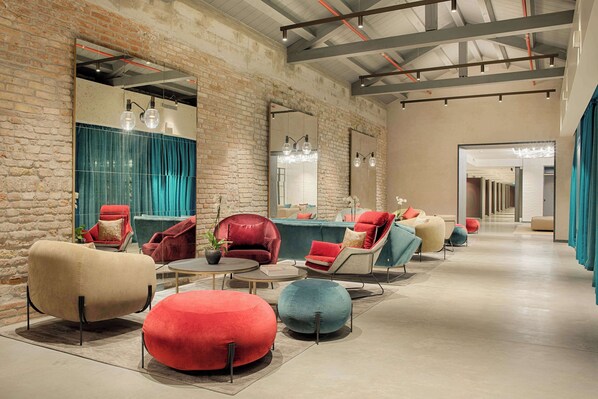 A modern lounge area with various seating options, including armchairs and ottomans, arranged on a polished floor. - NH Collection Venezia Murano Villa (Venice)