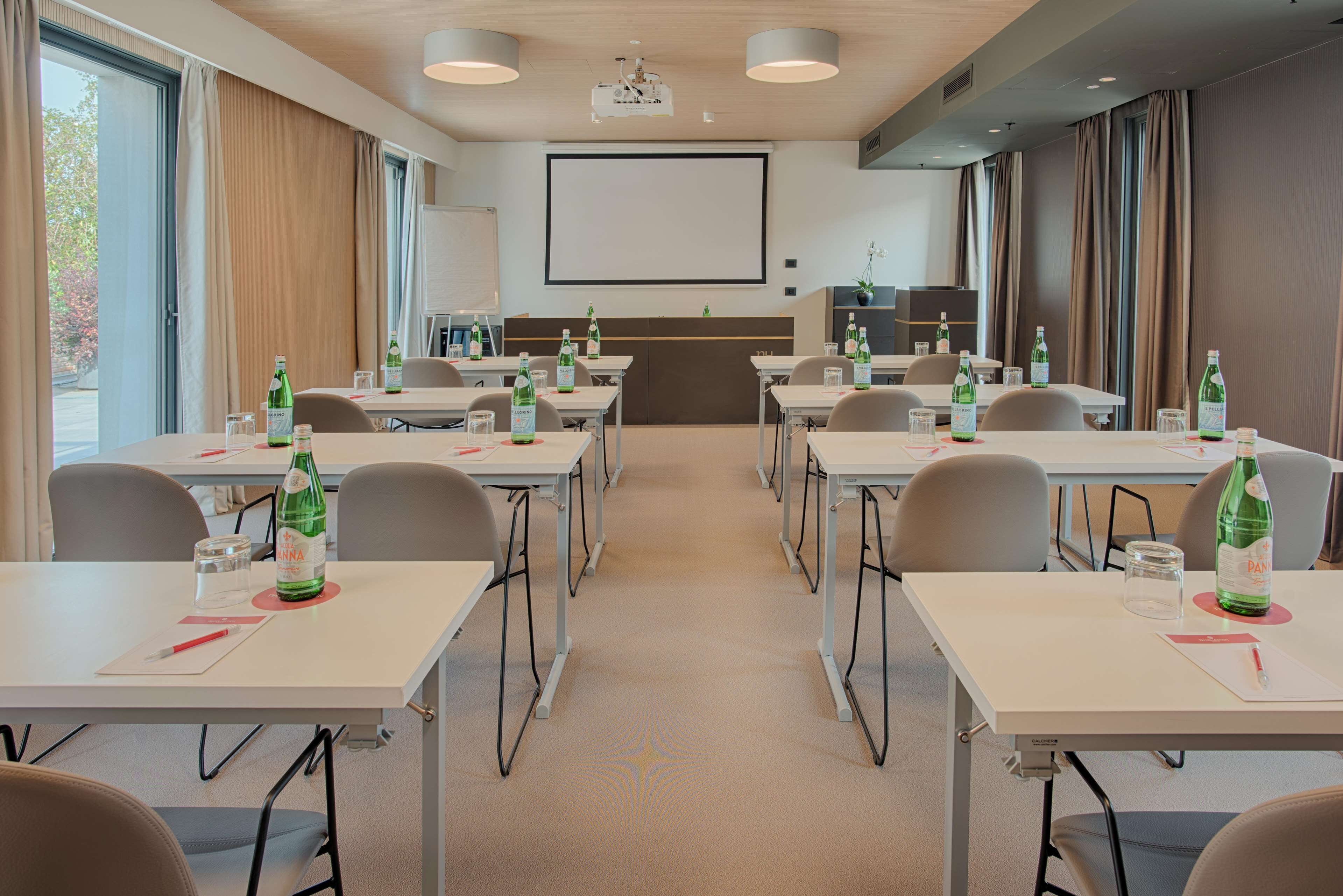 Une salle de conférence équipée de tables, de chaises et d’un écran de projection.