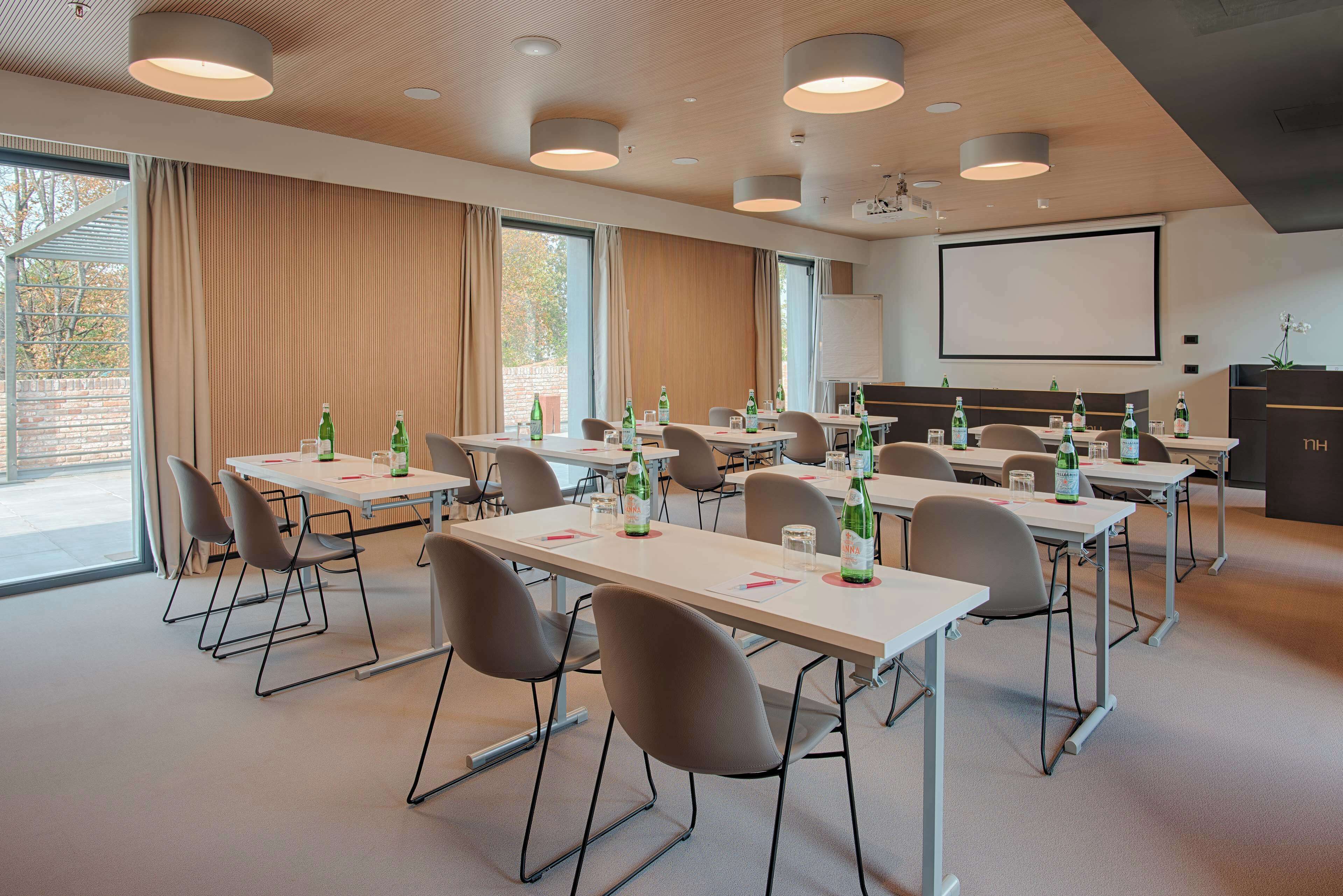 Una sala de conferències amb diverses taules, cadieres i una pantalla de projector.