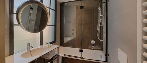 Un bagno moderno con uno specchio rotondo, un lavandino bianco e una cabina doccia in vetro.