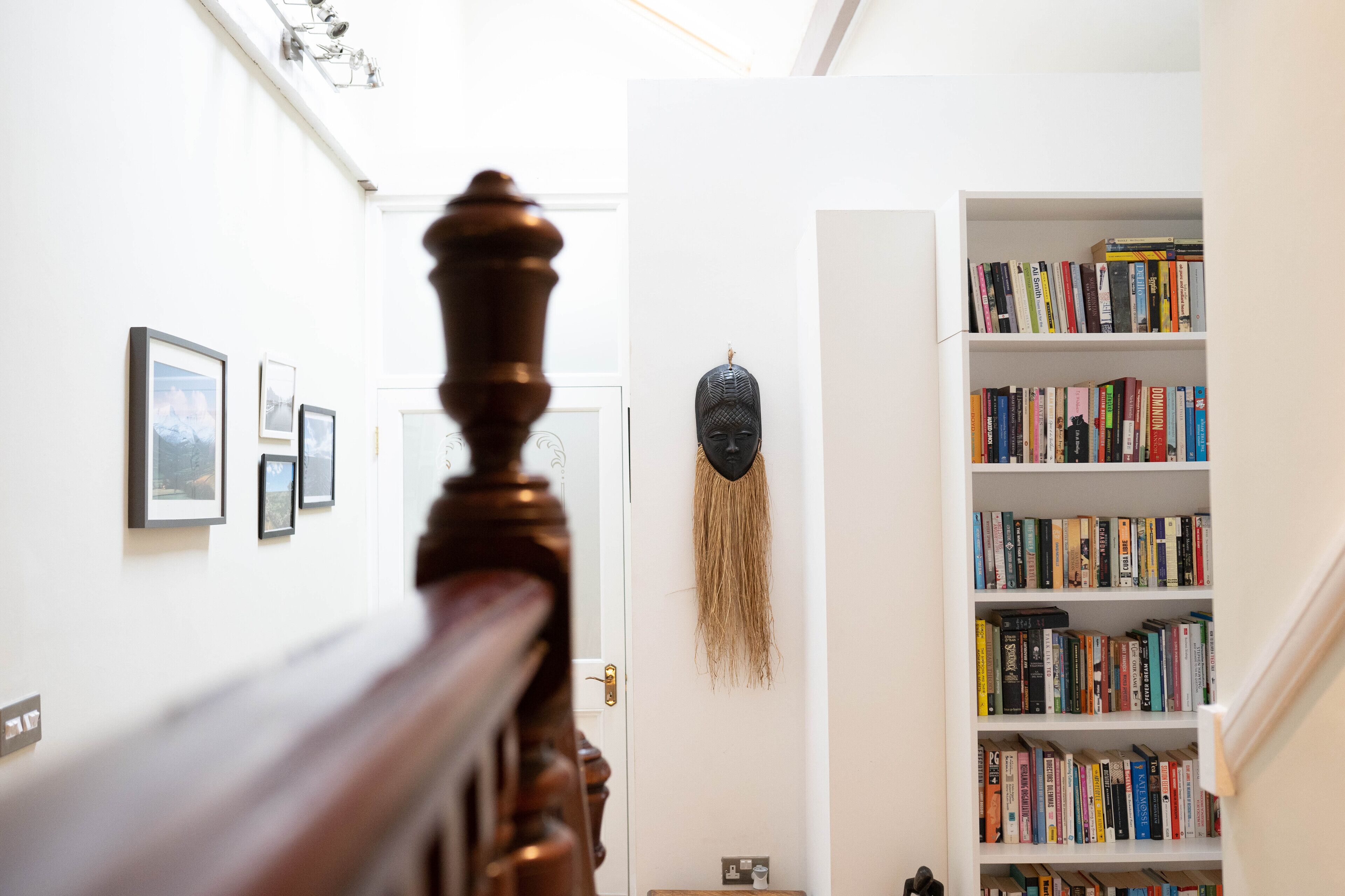 Een trap met een houten leuning die leidt naar een kamer met een boekenkast vol boeken.