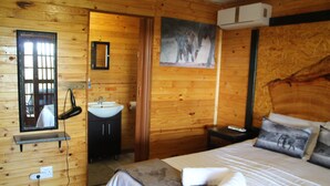 Une chambre à coucher aux murs lambrissés, avec un lit, une table de chevet, un miroir, un lavabo et un tableau accroché au mur.