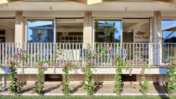 A hotel entrance with a white fence, a covered walkway, and pink flowering plants.