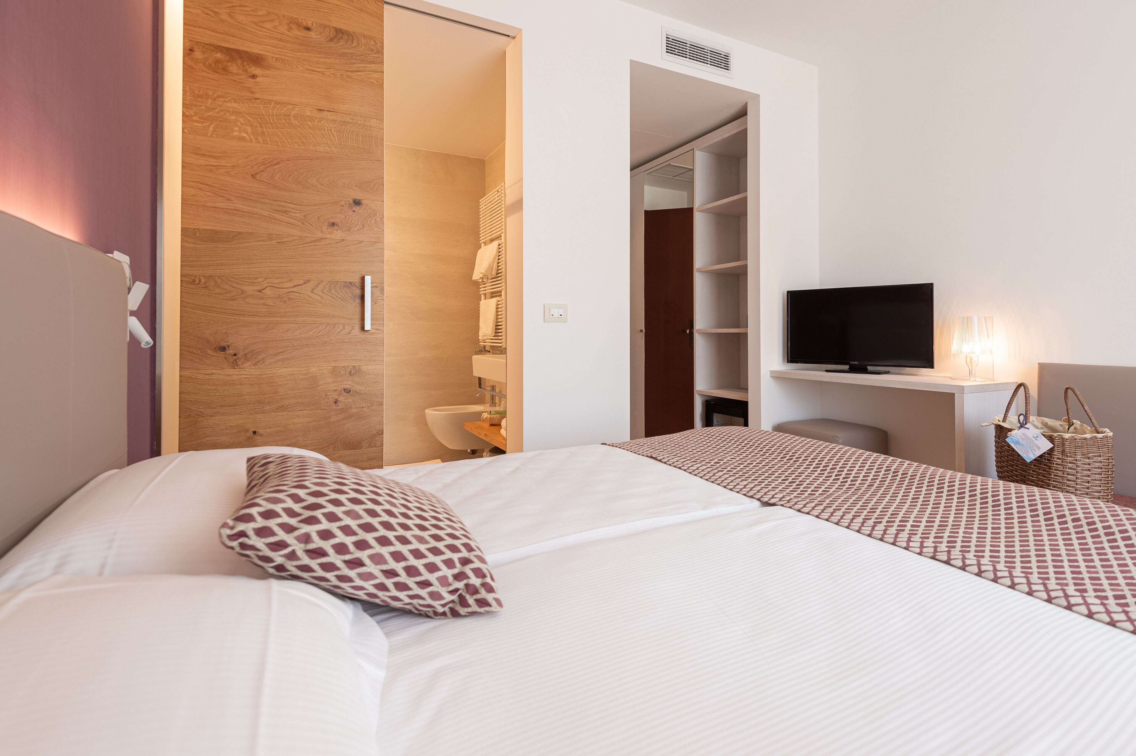 A hotel room with a bed, a TV, a wardrobe, and a bathroom.