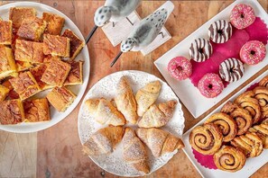 Diversa selección de pastelería que incluye cruasanes, danesas y rosquillas, dispuestas en platos.