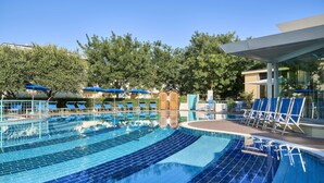 A swimming pool with clear blue water, surrounded by lounge chairs and umbrellas. - Junior Family Hotel (Cavallino-Treporti)