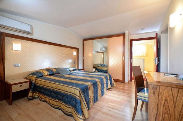 A bedroom with two beds, a wooden desk, and a chair. - Junior Family Hotel (Cavallino-Treporti)