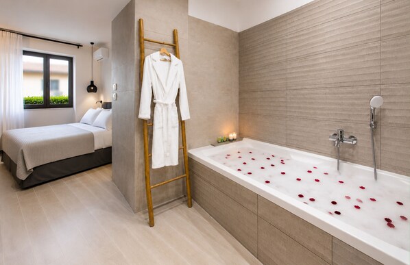 Een moderne badkamer met een badkuip, douche en een houten trapje met een badjas.